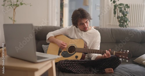 Immerse in the joy of a young musician crafting warm melodies while playing guitar at home