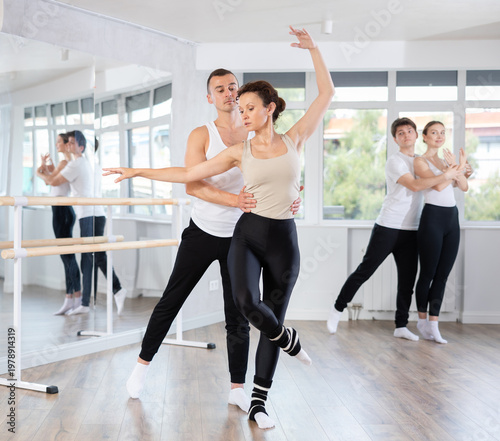 Young man and adult woman perform paired ballet dance in studio