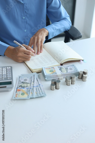 Billede på lærred Three stacks of coins arrange separated on the table while businessman writing in a notebook