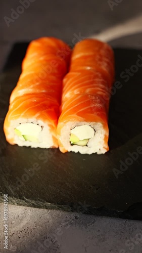 Fresh salmon sushi served on a black slate plate illuminated by soft natural light creating an inviting culinary scene