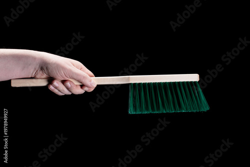 Hand holding broom on black background 