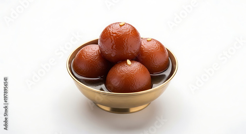 Perspective studio shot of four juicy Gulab Jamun dessert balls garnished with melon seeds, served in a traditional antique brass bowl filled with sweet aromatic syrup, representing luxury South Asian