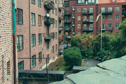 Courtyard of a brick apartment building with the Swedish flag and lush greenery