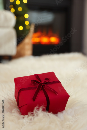 Red gift box on fluffy carpet indoors, closeup. Space for text