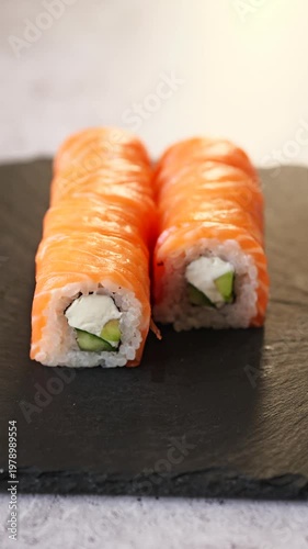 Delicious salmon sushi rolls served on a sleek black slate plate in a sunlit setting