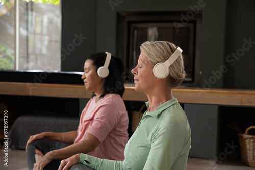 Photos Mature female participants meditating cross-legged in calm wellness space with w