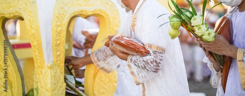 A temple marker stands above arranged lotus incense and candles as fresh lotus bundles and folded robes rest nearby with a blurred statue adding depth to the warm sacred ceremonial setting.