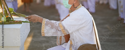 A temple marker stands above arranged lotus incense and candles as fresh lotus bundles and folded robes rest nearby with a blurred statue adding depth to the warm sacred ceremonial setting.