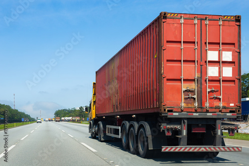 Cargo container truck driving on a highway during a sunny day, representing transportation, logistics, freight delivery, and road travel.