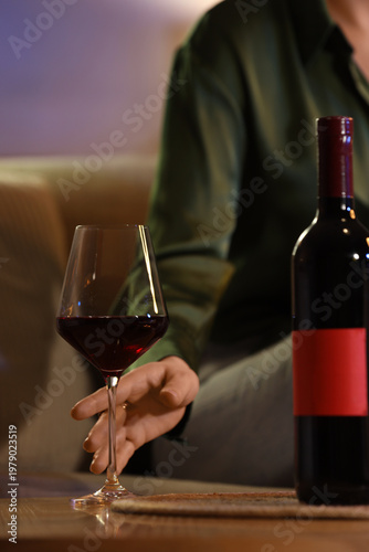 Bild auf Leinwand Woman taking glass of red wine from table at home late in evening, closeup