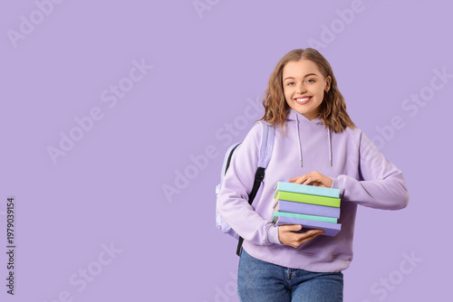Female student with stack of books on lilac background