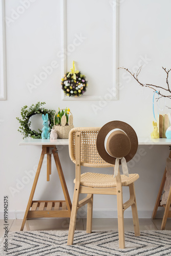 Workplace with Easter wreaths and rabbits near light wall in office