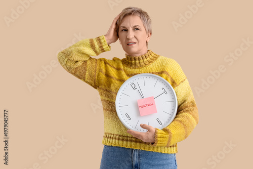Mature woman holding clock ...