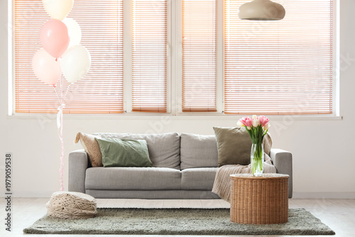 Interior of living room with sofa, balloons and tulips for Women's Day