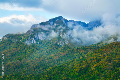 Green mountains contrast with the blue sky and a light mist.