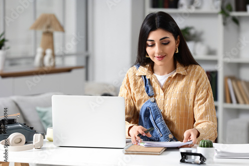 Female screenwriter writing script at table in office