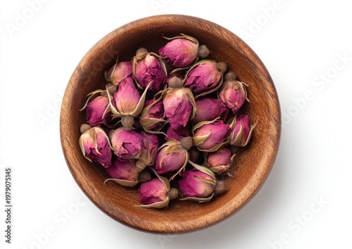 Small, dried rose buds are piled in a wooden bowl against a white background
