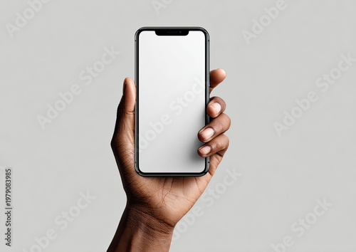 Dark hand holds modern smartphone with blank white screen against light grey background