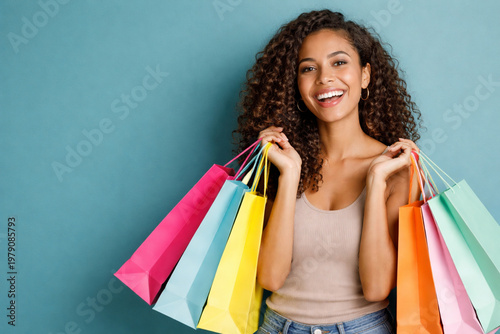 Medium shot of a smiling woman of mixed ethnicity holding colorful shopping bags-