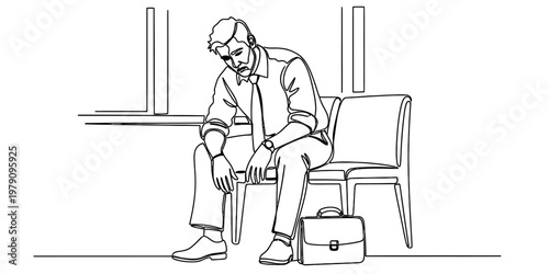 A tired businessman sits on a chair in a waiting area looking down at the floor in deep thought