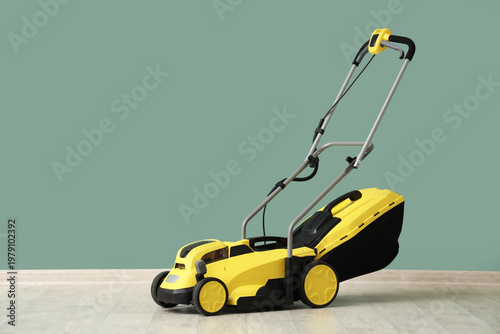 Lawn mower near green wall ...