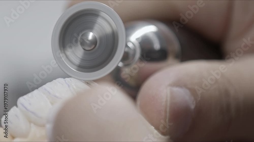 Extreme close up of a dental technician using a professional polishing tool on a ceramic tooth crown. Precise laboratory work in dentistry, ideal for medical and healthcare projects.