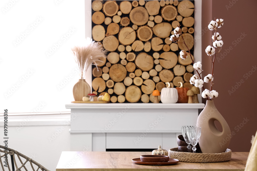 Naklejka premium Vase with cotton flowers and dishes on dining table in room