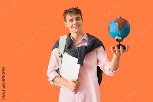Male student with laptop and globe on orange background