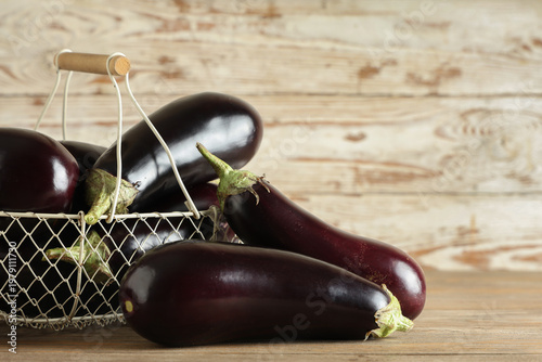 Basket with fresh eggplants on wooden background