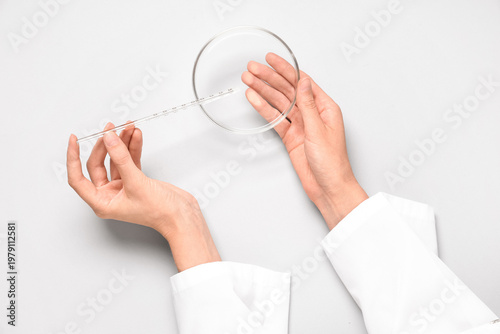 Scientist working with graduated dropper and Petri dish on grey background