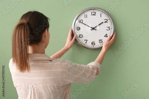 Young woman hanging clock o...