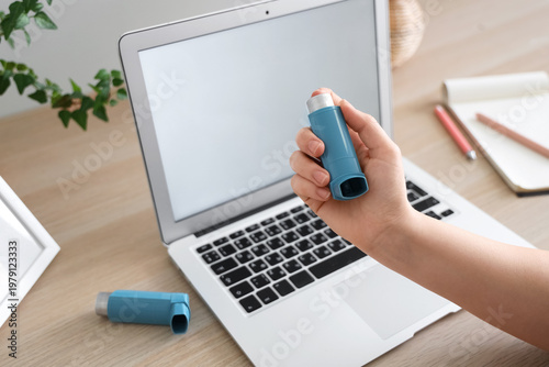 Foto Woman with modern inhaler and laptop at workspace, closeup