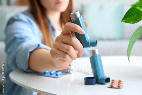 Bild auf Leinwand Woman taking modern inhaler from table with pills in living room