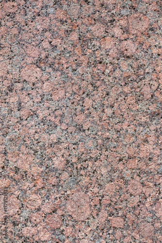 Granite texture. Natural pink granite with a grainy pattern. Stone background. Solid rough surface of rock. Durable construction and decoration material. Close-up.