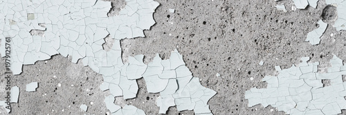 Peeling paint on the wall. Panorama of a concrete wall with old cracked flaking paint. Weathered rough painted surface with patterns of cracks and peeling. Panoramic texture for background and design.
