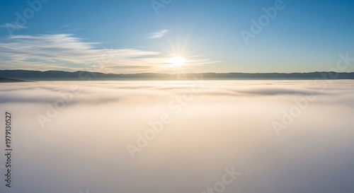 Sunrise over foggy landscape with clouds.