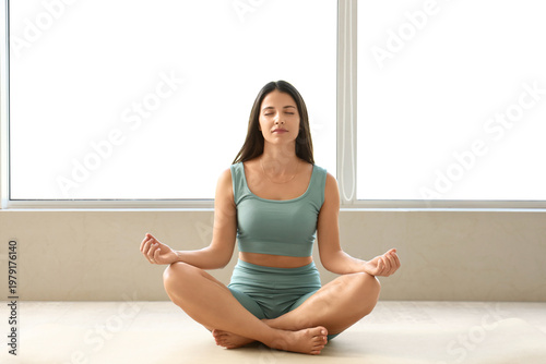 Sporty young woman meditating at home in morning