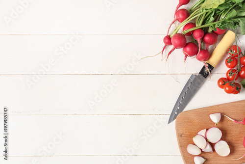 Composition with fresh radish, tomatoes and knife on light wooden background