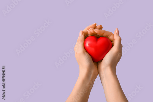 Female hands with heart on lilac background. Valentine's Day celebration