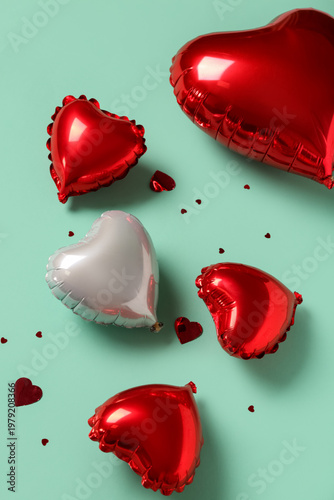 Heart shaped air balloons and confetti on green background. Valentine's Day celebration