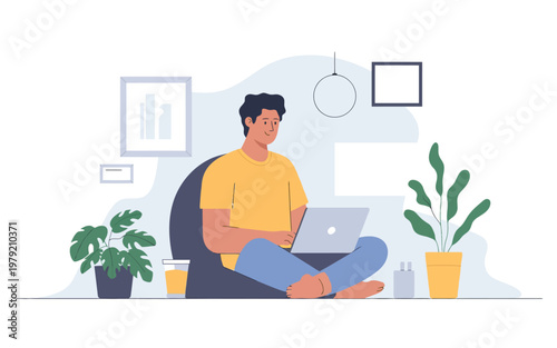 A young man comfortably working on a laptop at home relaxing indoors