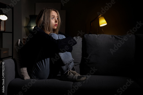 Depressed young woman in dark room at night