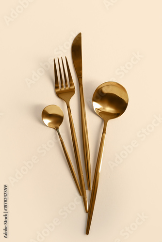Golden cutlery on beige bac...