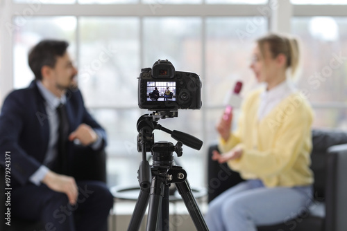 Photos Female journalist with microphone having an interview with man on camera screen