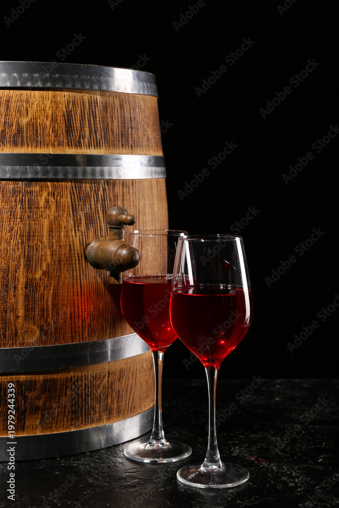 Naklejka premium Wooden barrel with glasses of wine on dark background