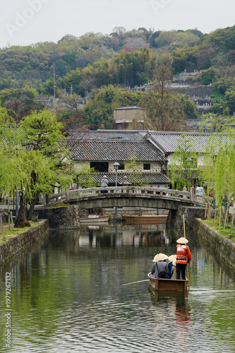 Historic Japanese Canal Boat Tour With Tourists Passing Under Stone Bridge