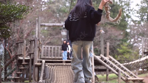 Slow motion of a boy playing on a zip line or rope swing at an outdoor adventure park, rear view.