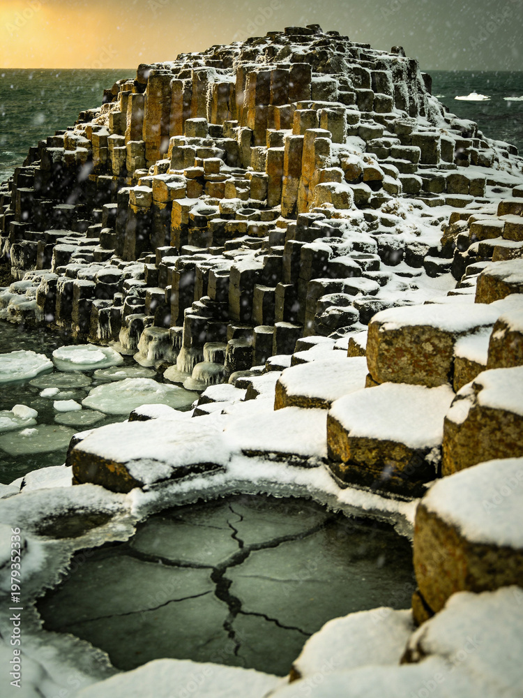 Fototapeta premium Atmospheric Basalt Formations Under Dramatic Skies and Ocean Spray