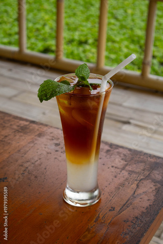 Refreshing layered iced tea mocktail with mint garnish on wooden table
