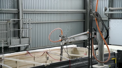 The truck is inside a large warehouse or hangar. A truck with a trailer that is used to transport bulk materials.